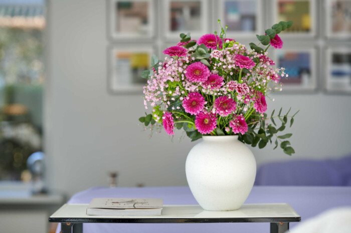 Sfeerfoto van Gerbera Pomponi® Mini Snuffy met opvallende hot pink bloemen in een witte vaas